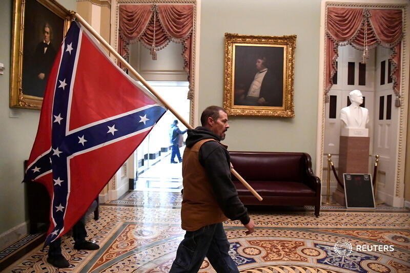 A man carries a Confederate battle flag into the U.S. Capitol building in a blatant racist display of American terrorism.